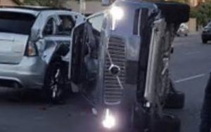 Two damaged vehicles after a collision; one overturned, headlights on; another with severe side damage.