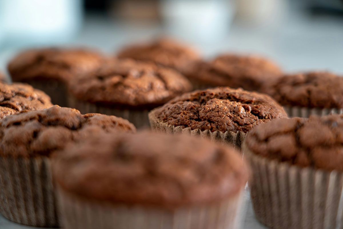A bunch of chocolate muffins are sitting on a table.