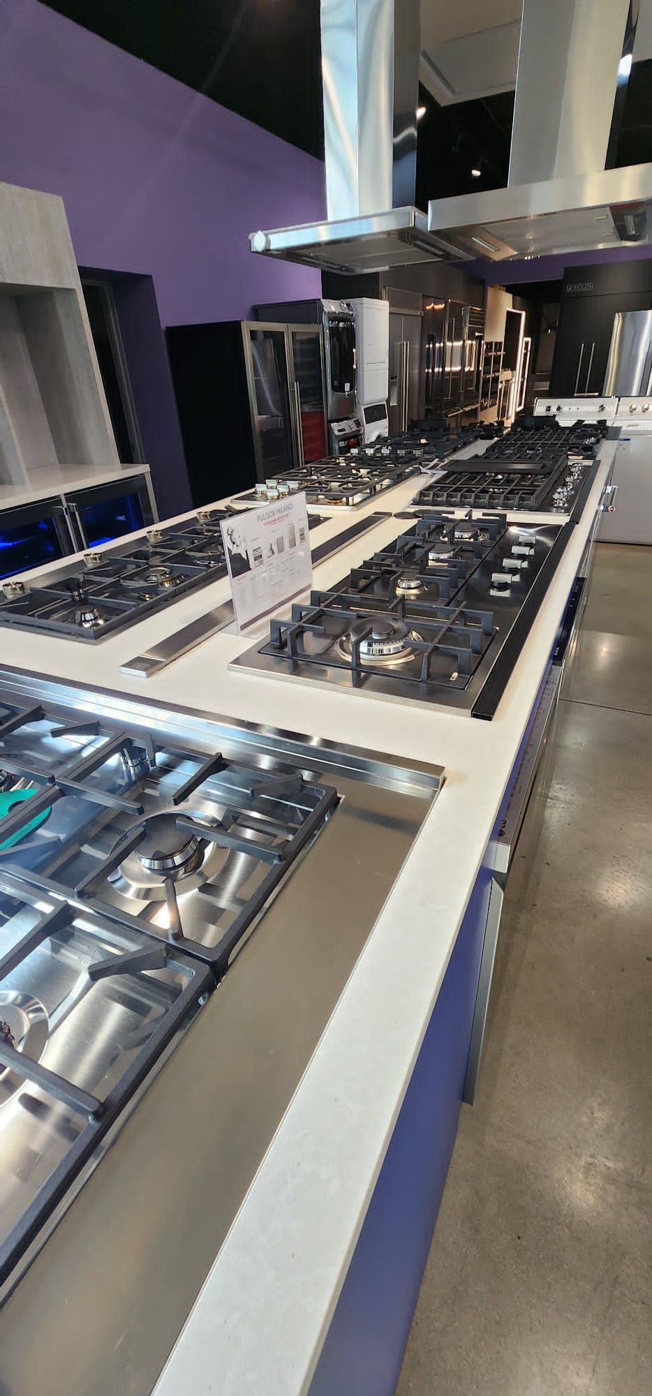 A row of stainless steel stove tops in a kitchen showroom.