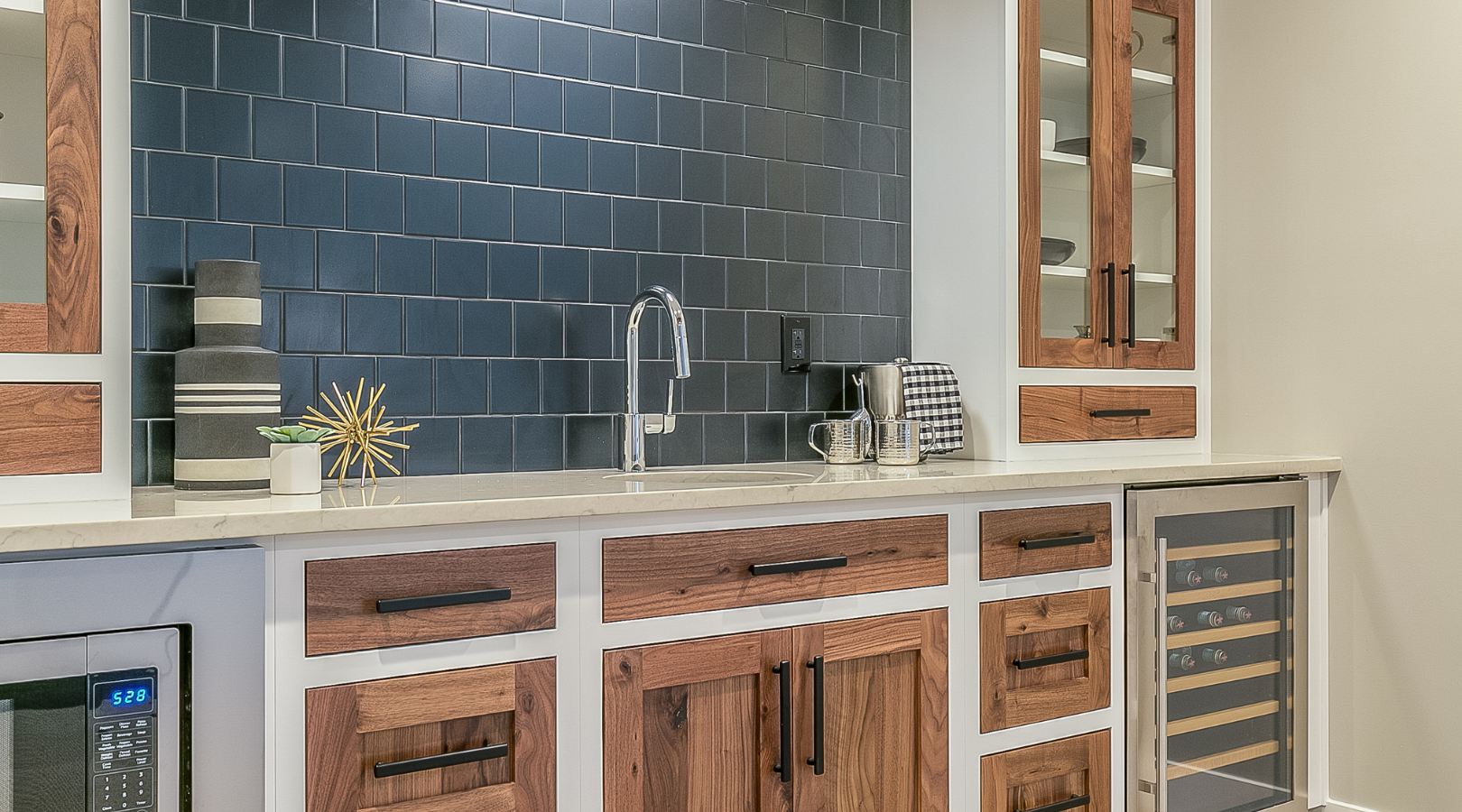 A kitchen with wooden cabinets , a sink , a microwave and a wine cooler.