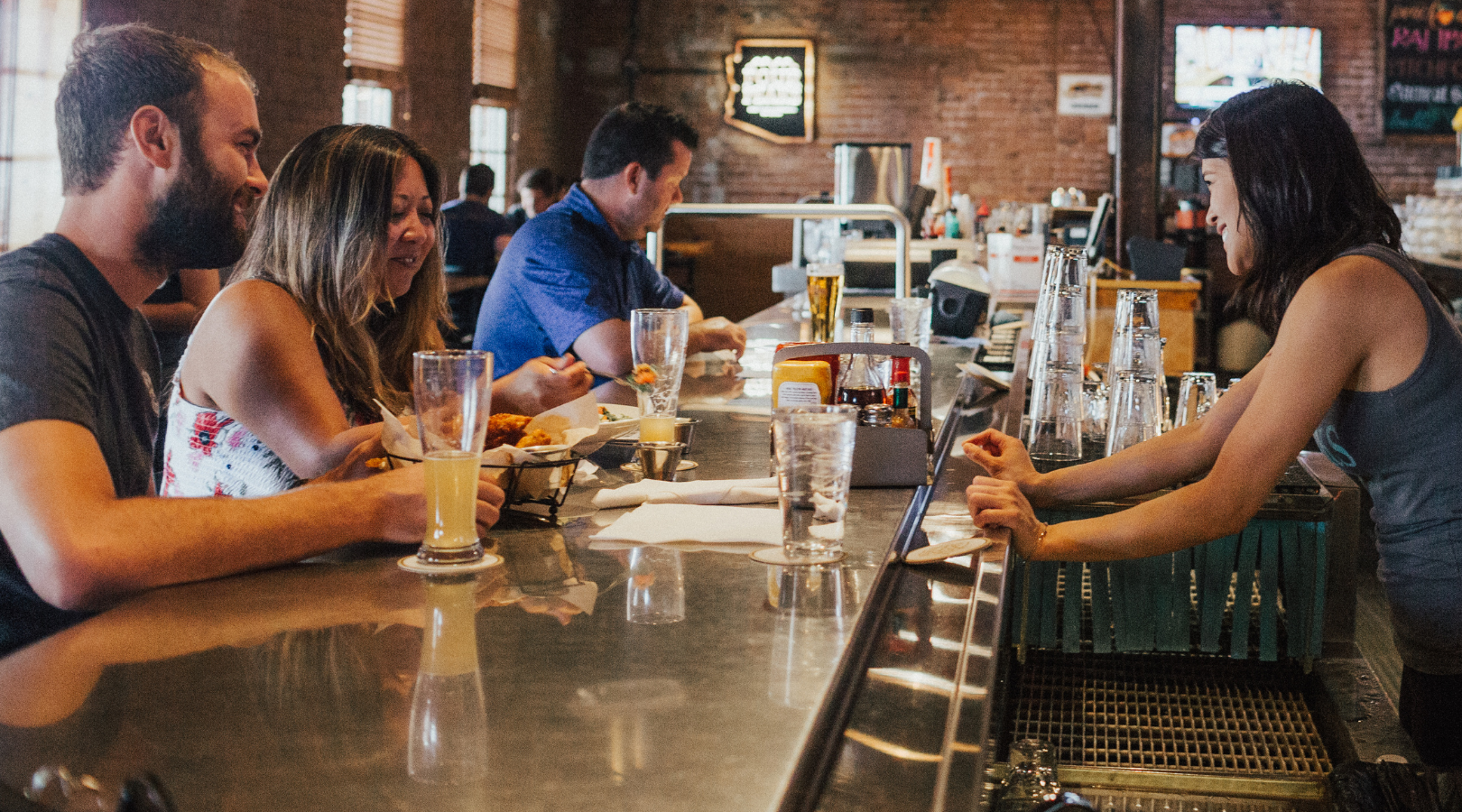 A group of people are sitting at a bar in a restaurant.