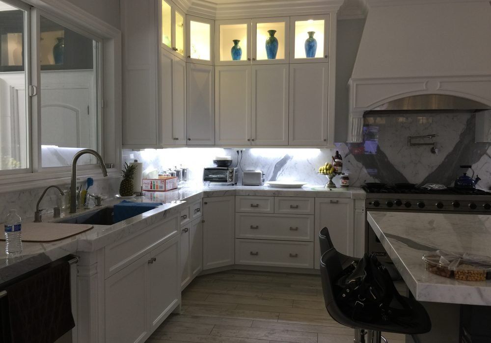 A kitchen with white cabinets , a sink , and a stove.