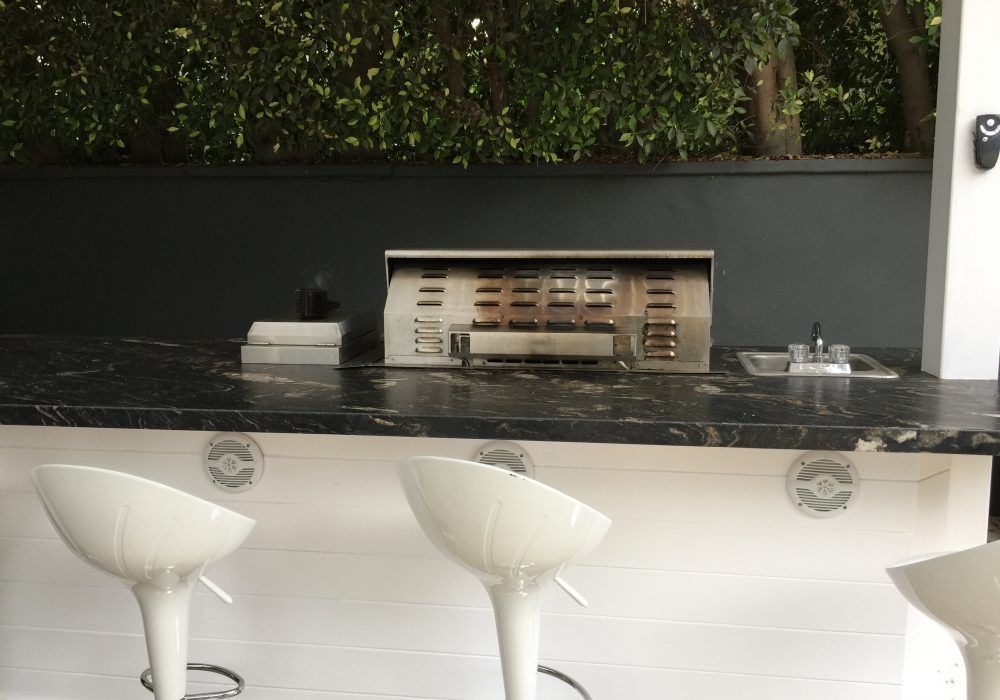 A kitchen with a grill and two bar stools.