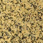 A close up of a yellow granite counter top with black spots.