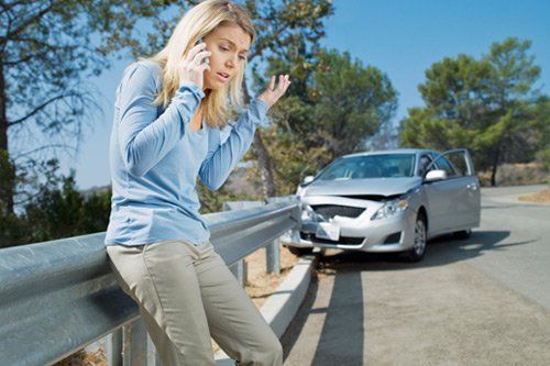 crashed car and woman talking with phone