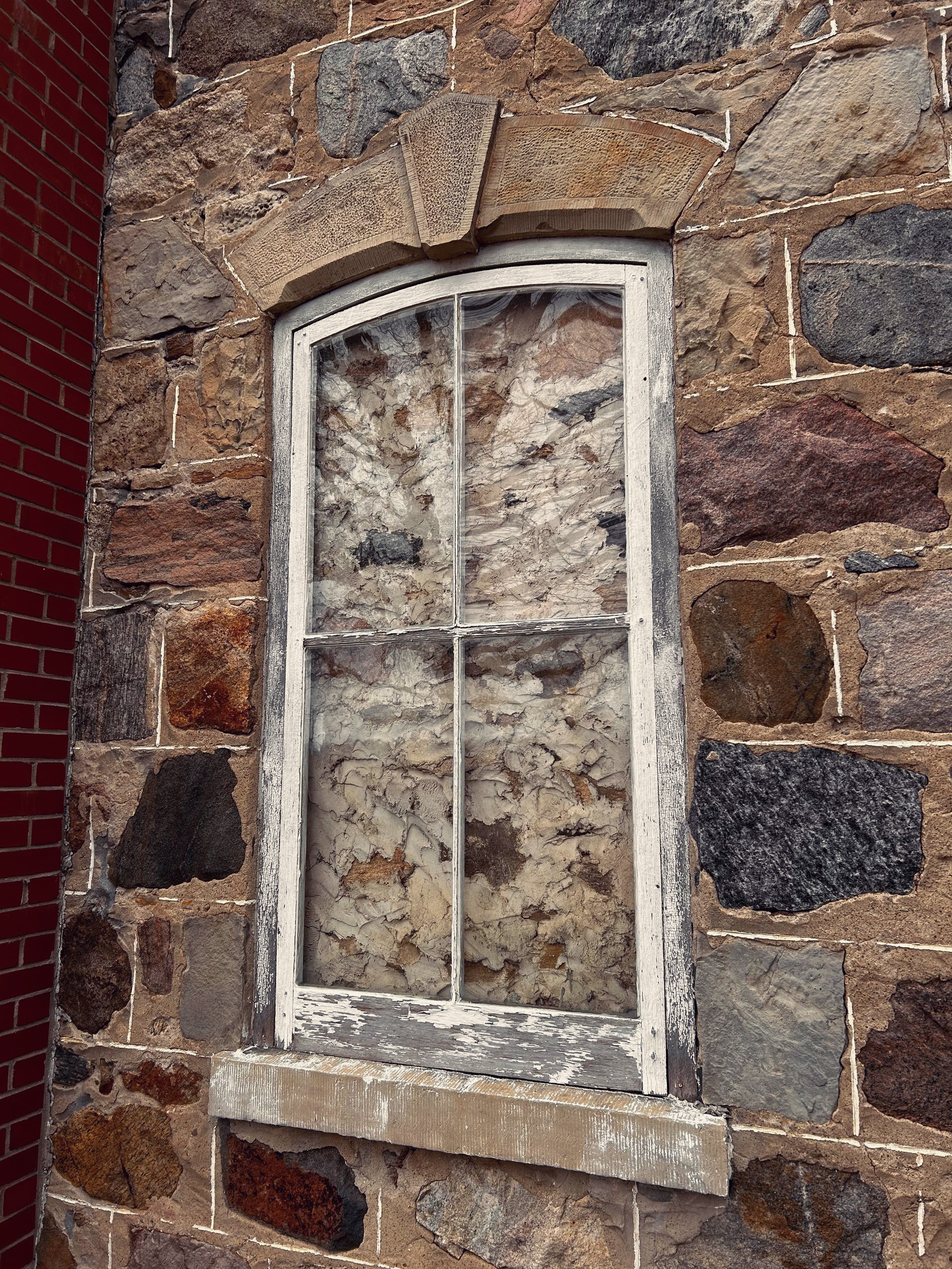 Small white-framed window set in a rough stone wall
