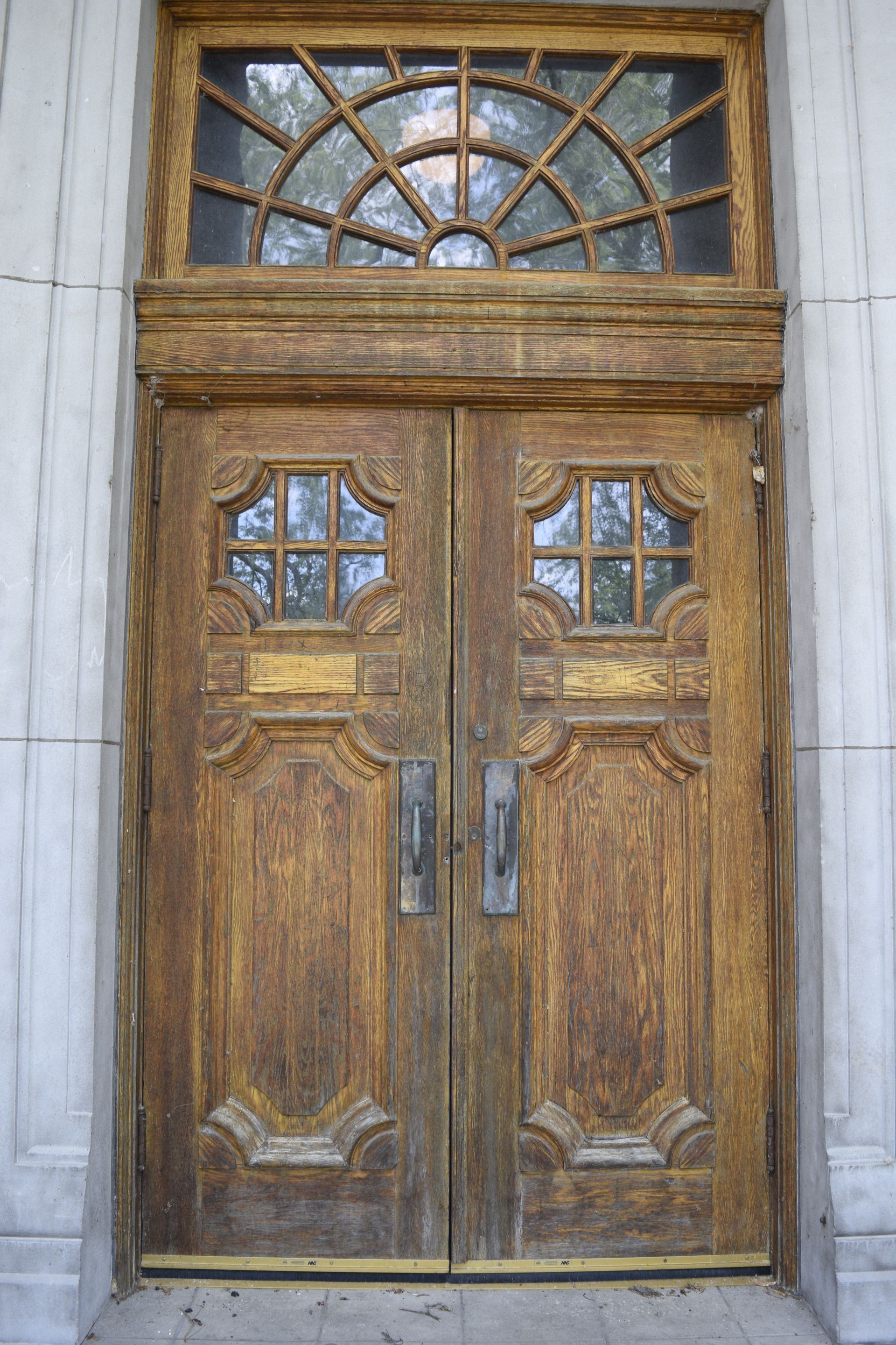 Wooden double doors with glass panels and metal handles on a stone building entrance