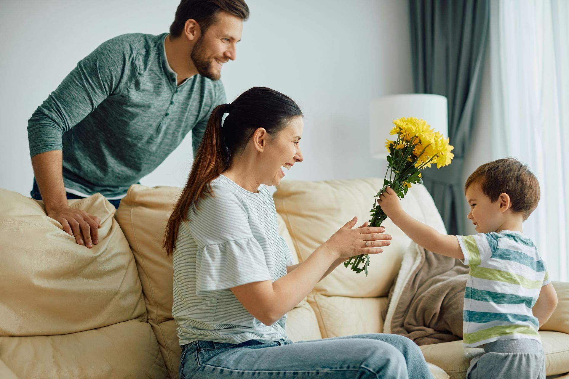 Couple in white t-shirts lying on a bed, looking at each other, smiling.