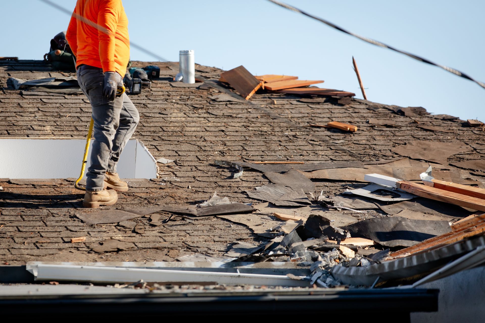 Worker using a nail gun to repair gray roof shingles