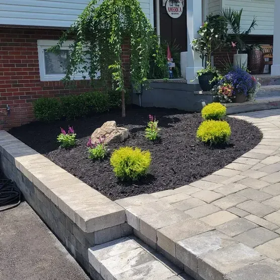 A brick walkway with a garden in front of a brick house.