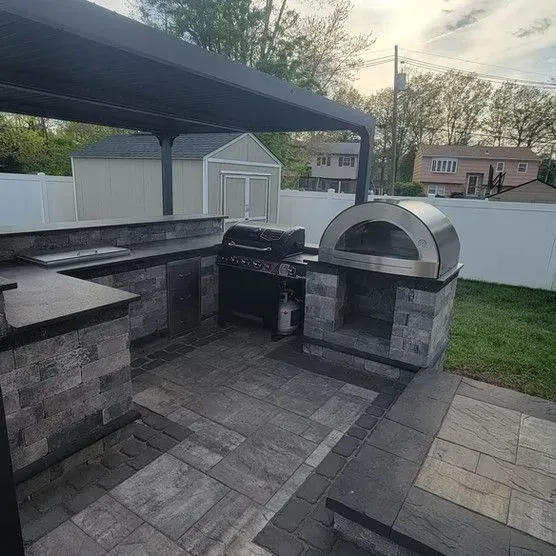 There is a grill and a pizza oven in the backyard.