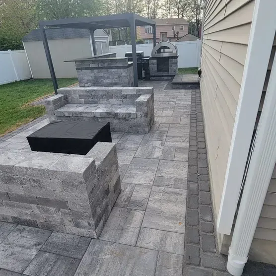 A patio with a fire pit and chairs next to a house.