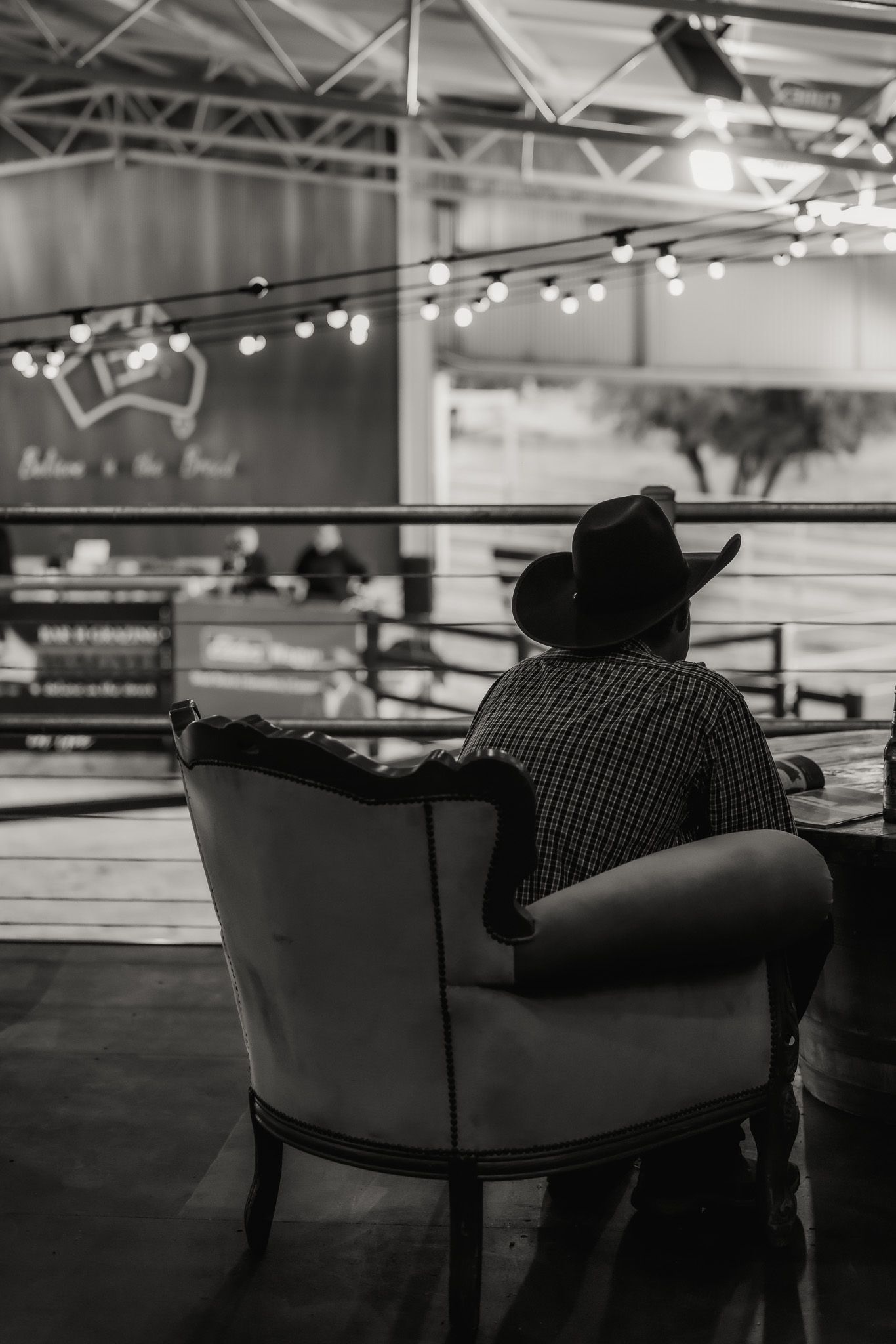 A man in a cowboy hat is sitting in a chair in a black and white photo.