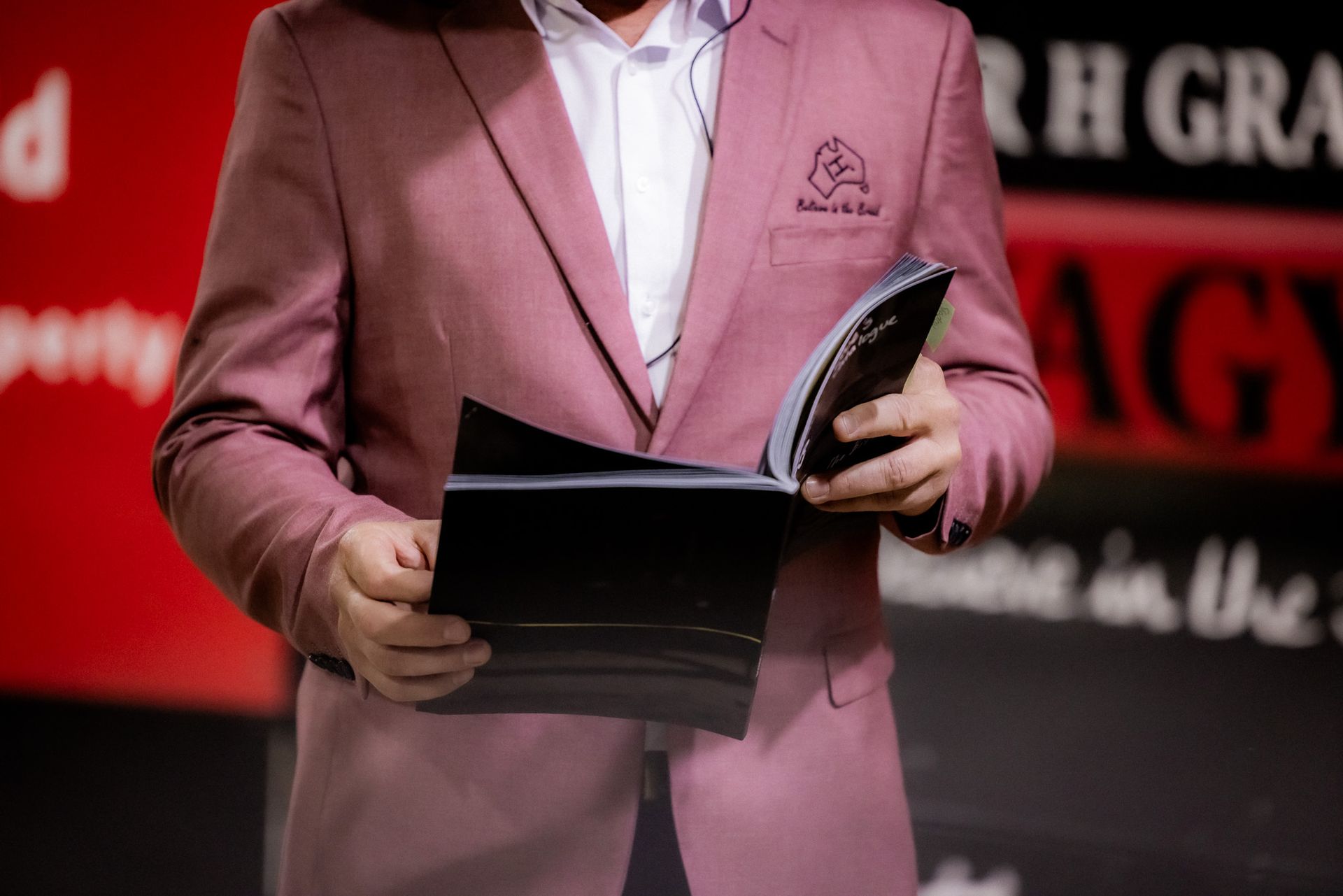 A man in a pink suit is holding a book in his hands.