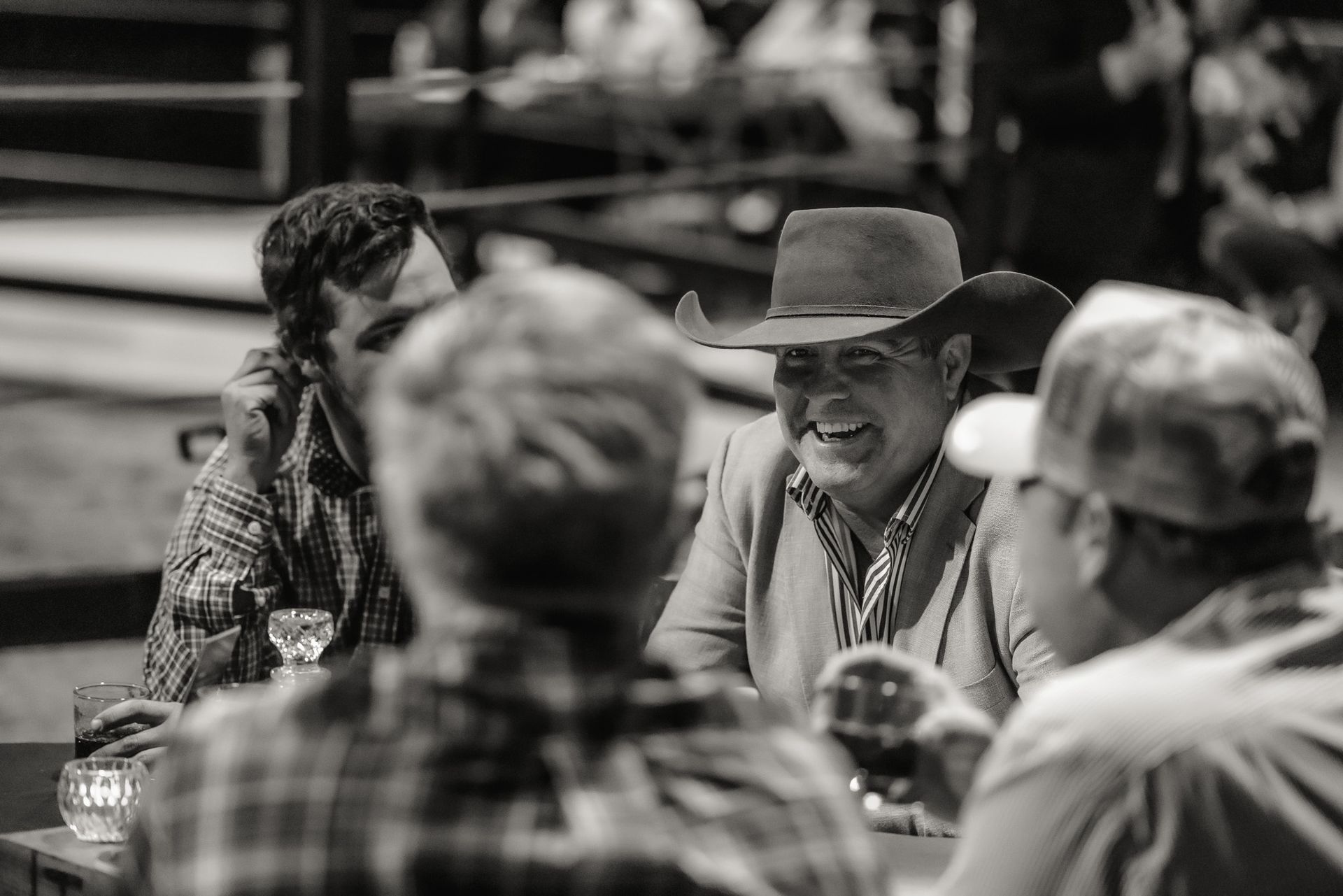 A group of men are sitting at a table laughing and drinking wine.