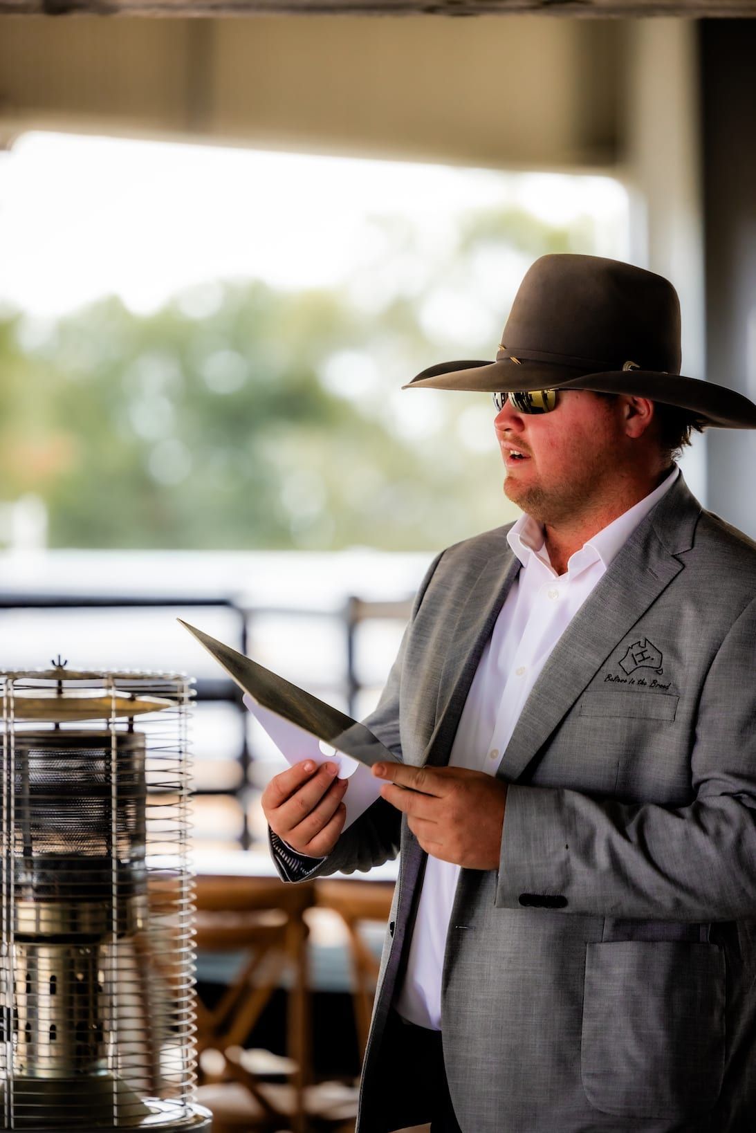 Man in a cowboy hat and suit jacket giving a speech outside.