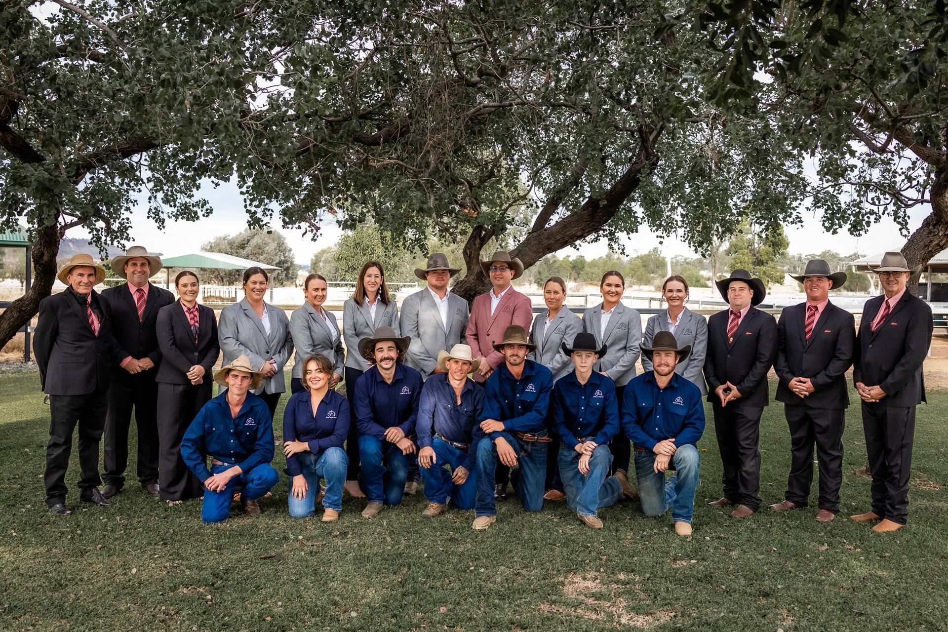 A group of people are posing for a picture under a tree.