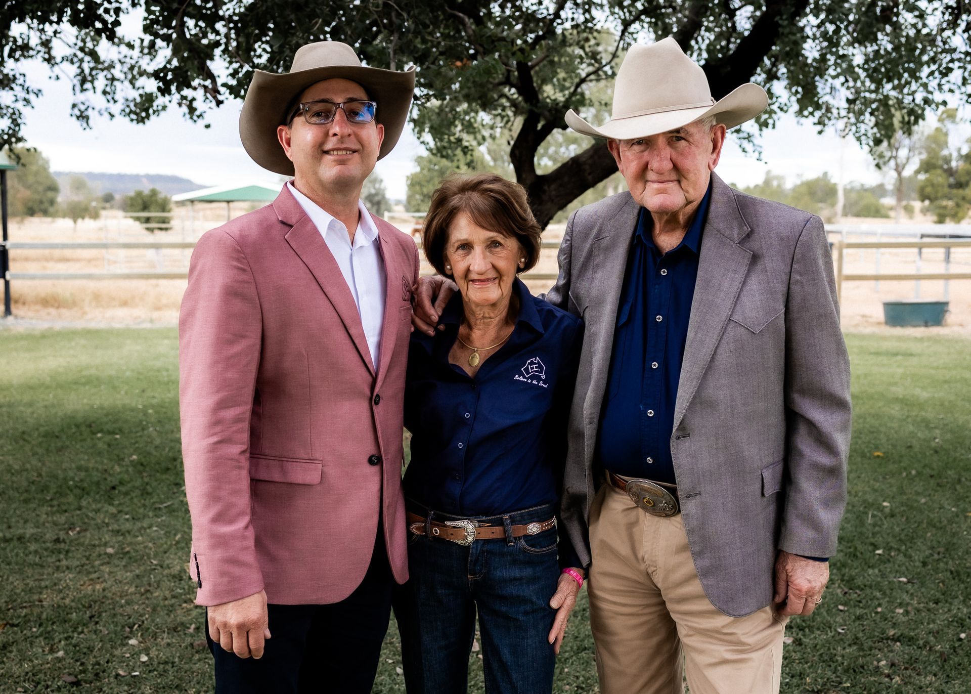 Two men and a woman are posing for a picture while wearing cowboy hats.