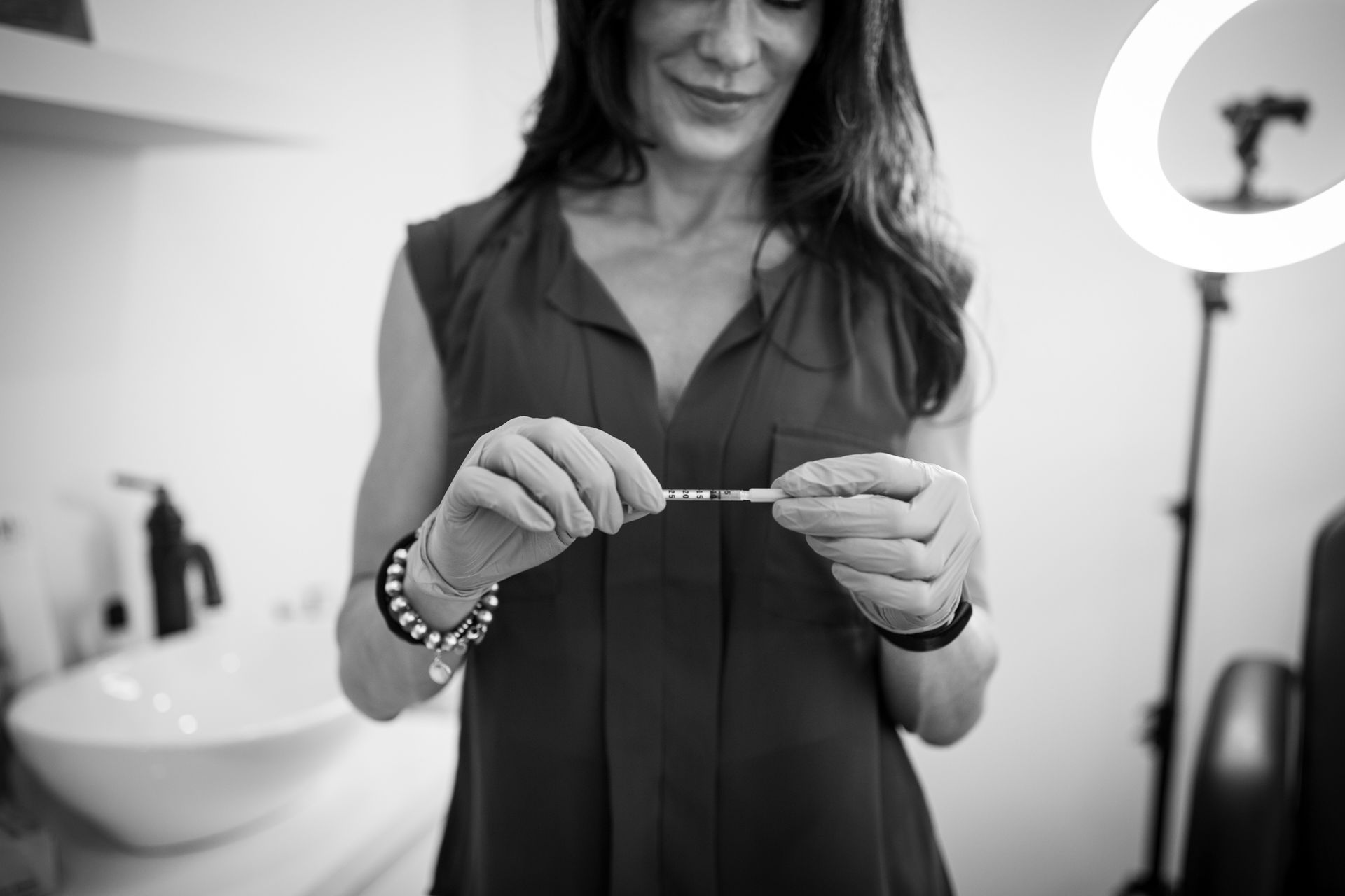 A woman is holding a bracelet in her hands in a black and white photo.