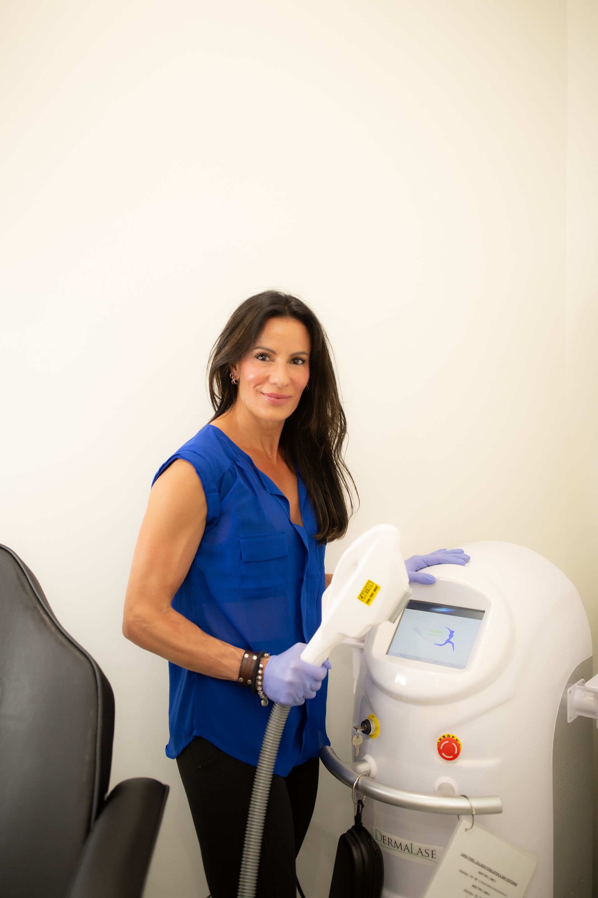 A woman in a blue shirt is standing next to a machine.