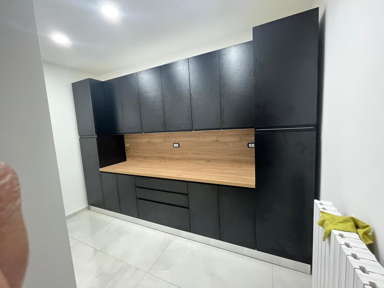 Una cucina con mobili neri e un piano di lavoro in legno.