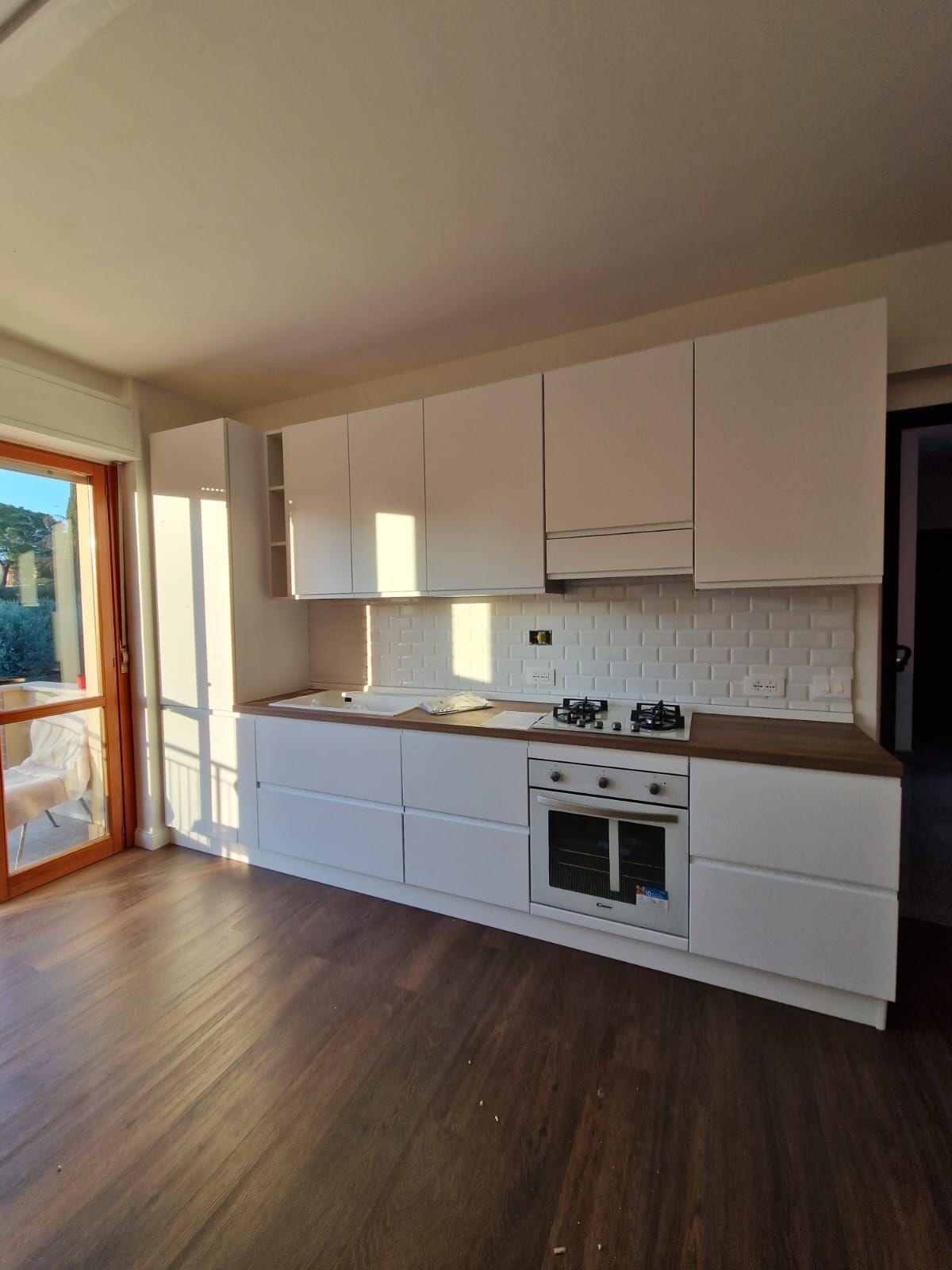 Una cucina con mobili bianchi e pavimento in legno