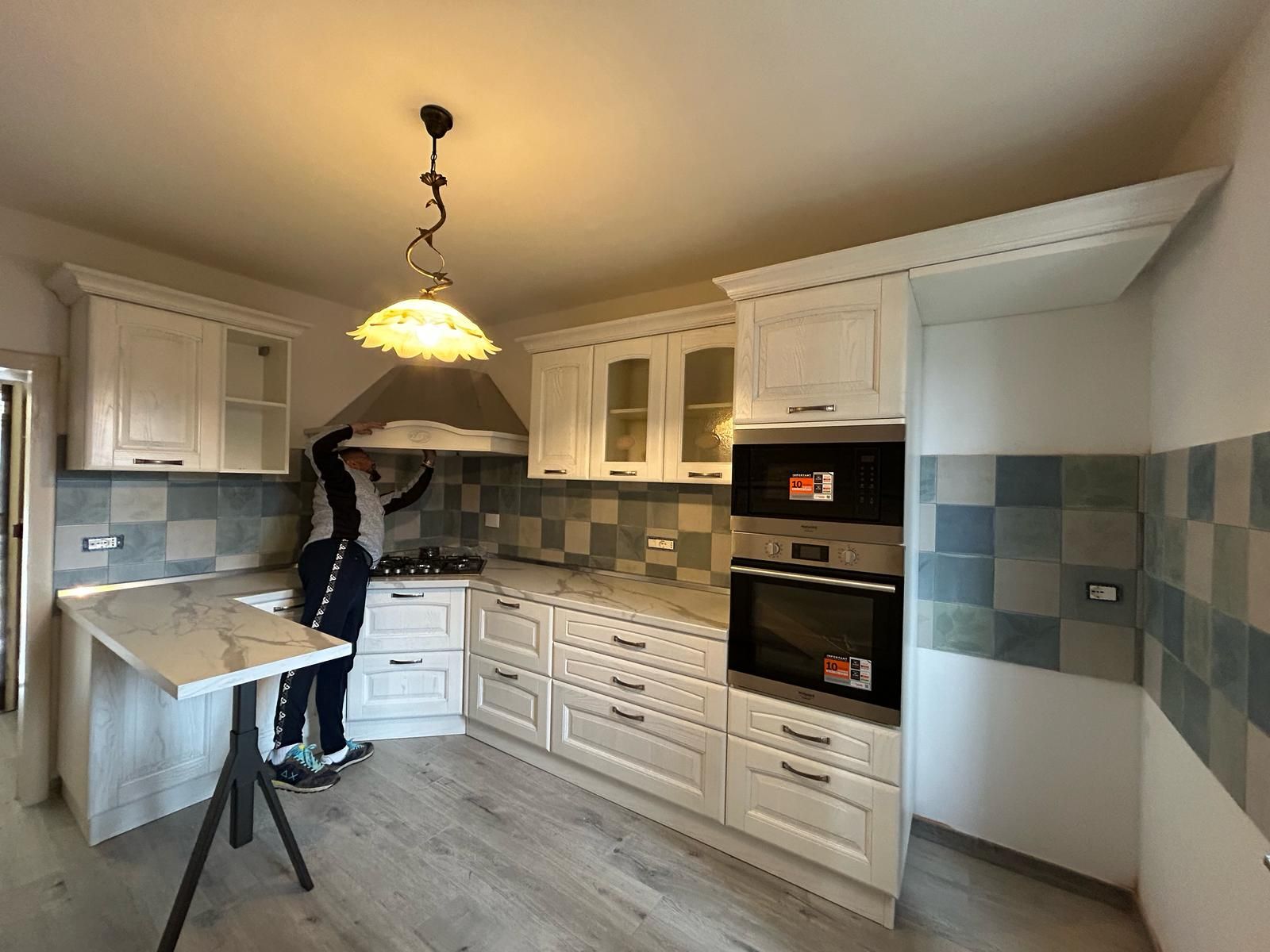 Un uomo è in piedi in una cucina con mobili bianchi.