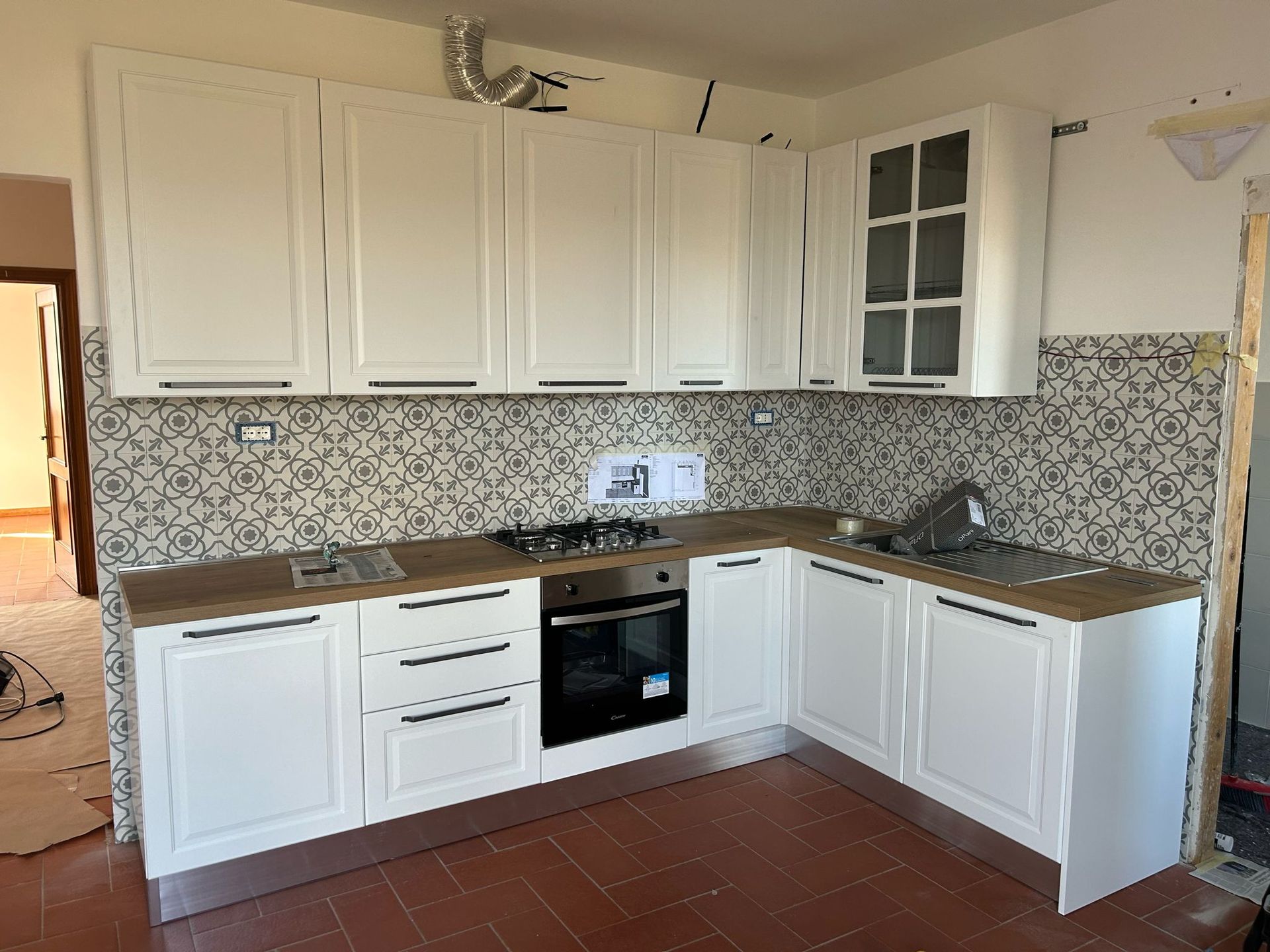 Una cucina con mobili bianchi e un forno a piano cottura