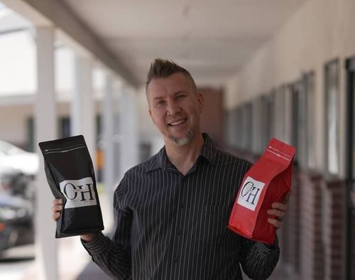 A man is holding two bags of ch coffee