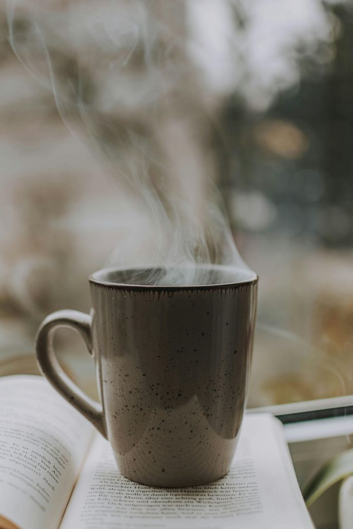 A cup of hot coffee is sitting on top of an open book.