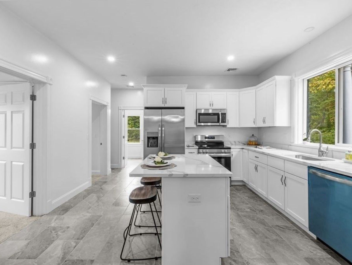 A kitchen with white cabinets , stainless steel appliances , and a blue dishwasher.