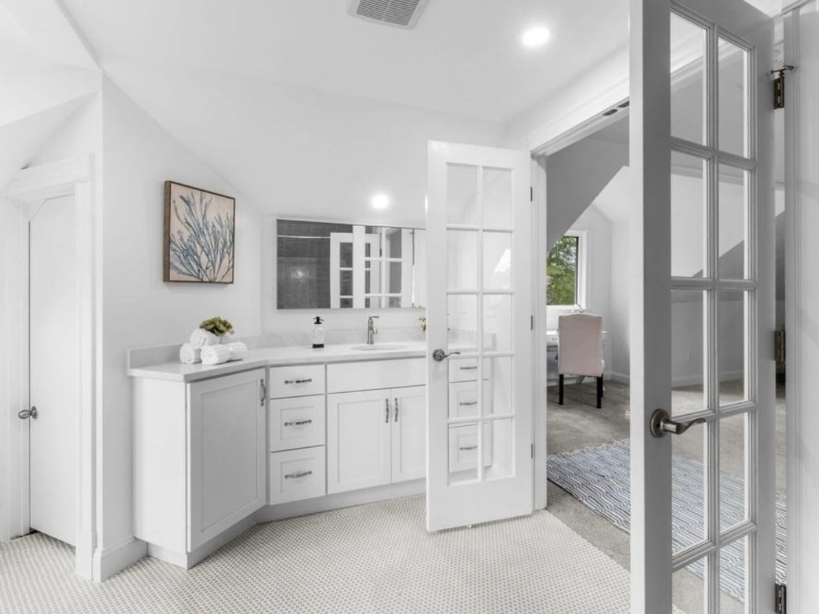 A bathroom with white cabinets and a french door