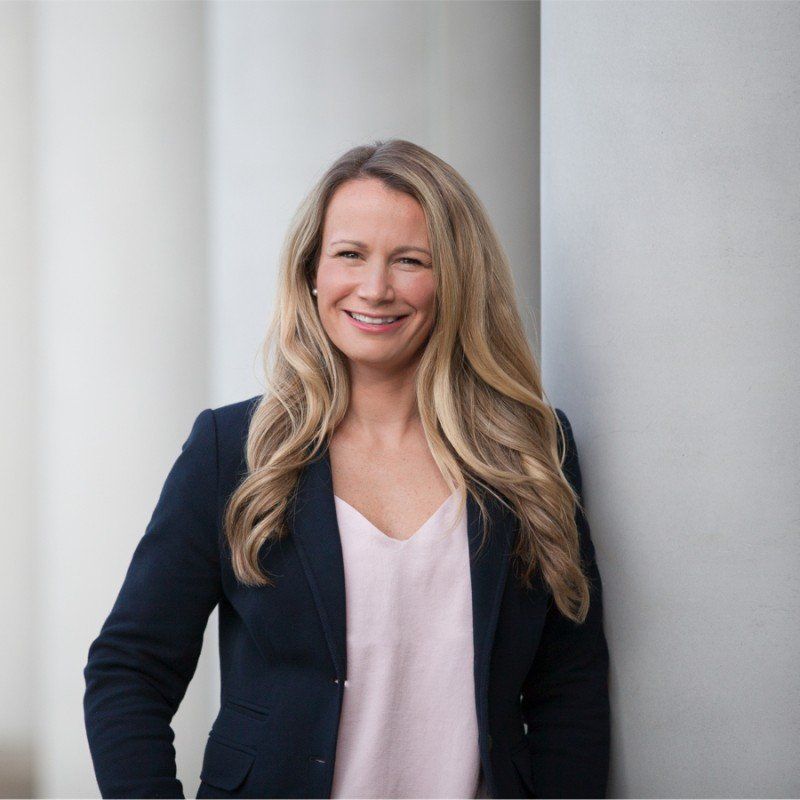 A woman is leaning against a wall and smiling