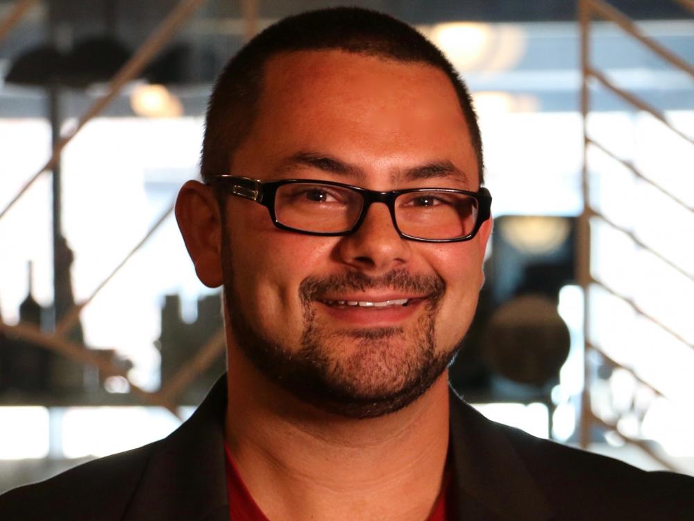 A man with glasses and a beard is smiling for the camera