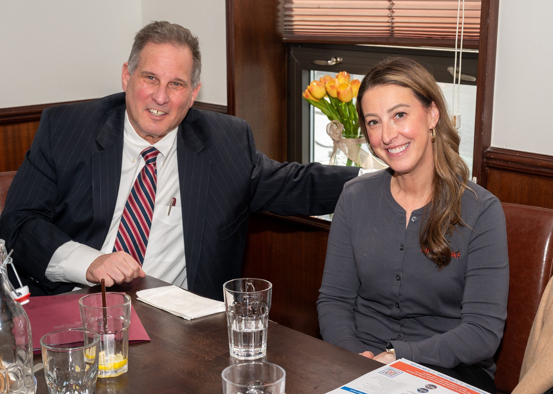 A man and a woman are sitting at a table with glasses of water.