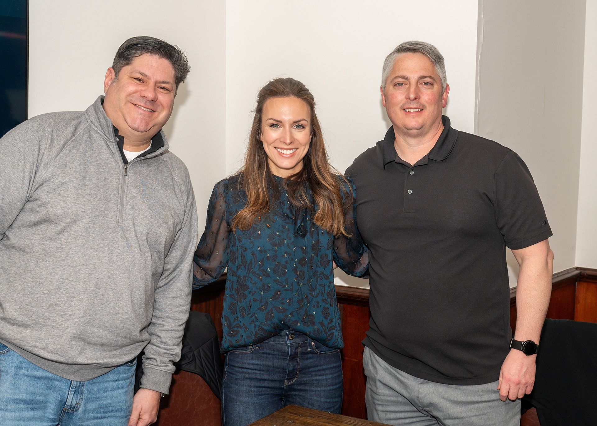 Three people are posing for a picture together in a room.