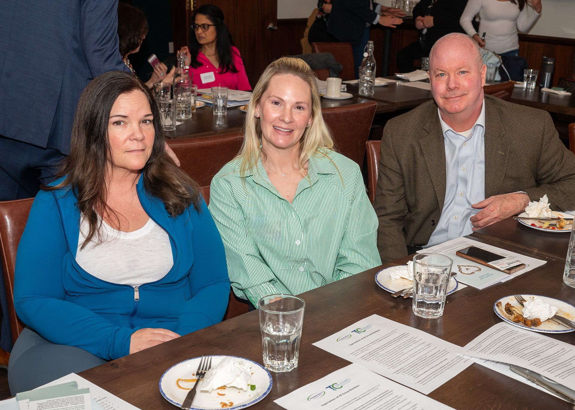 Three people are sitting at a table with plates of food and glasses of water.