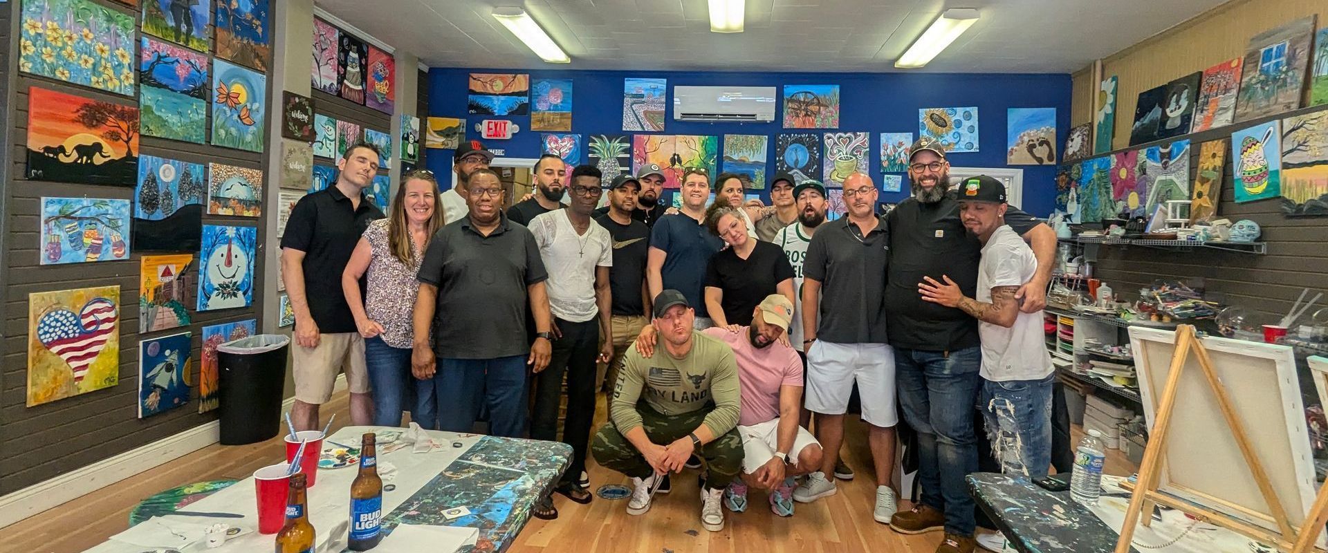 A group of people are posing for a picture in a room filled with paintings.