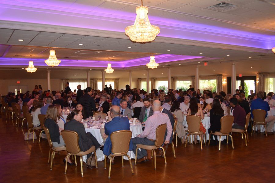 A large room filled with people sitting at tables and chairs.