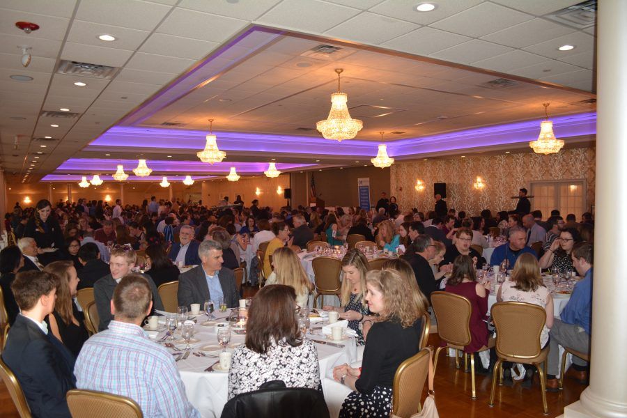 A large group of people are sitting at tables in a large room.