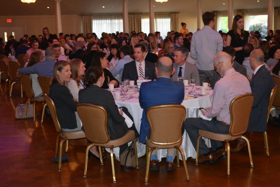 A large group of people are sitting around tables in a room.