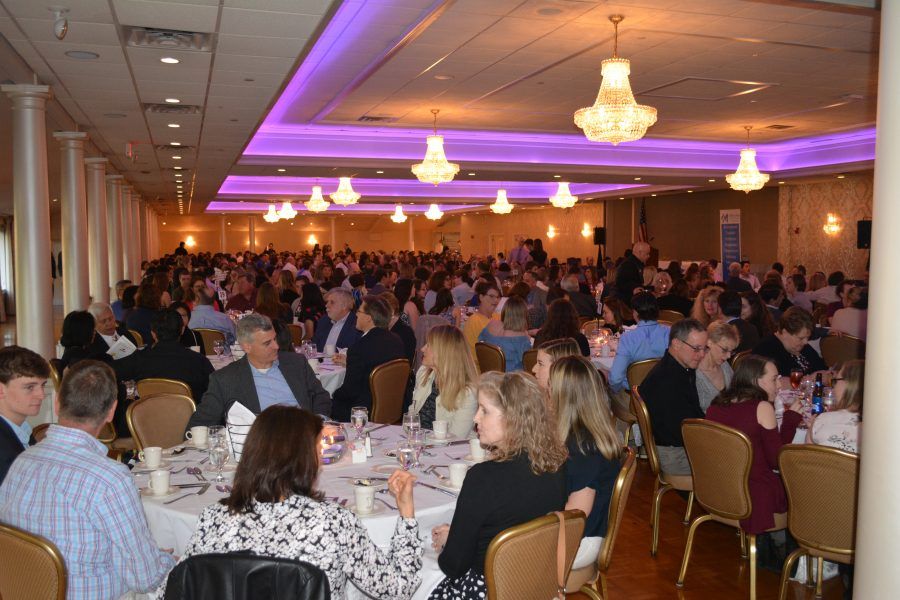 A large group of people are sitting at tables in a large room.