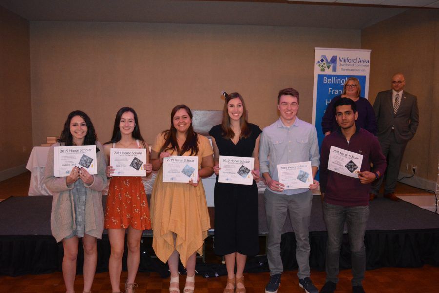 A group of people are standing on a stage holding certificates.