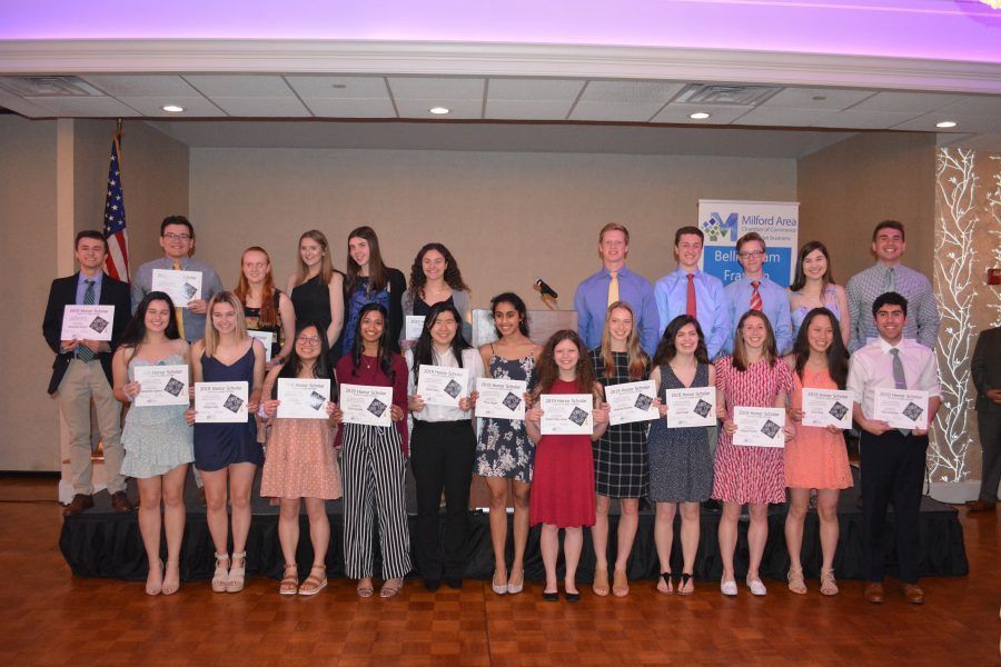 A group of people standing on a stage holding certificates.