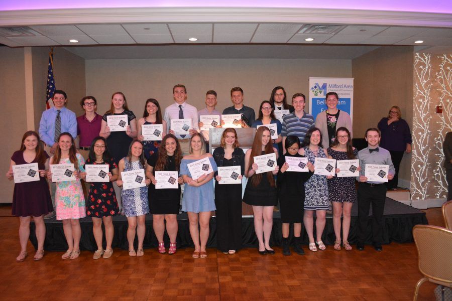 A group of people are standing on a stage holding certificates.