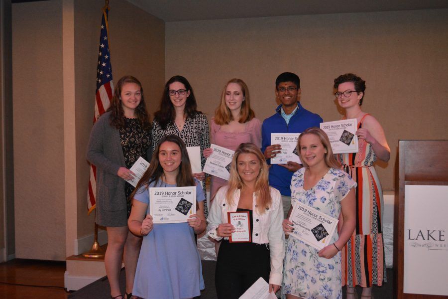 A group of young people are posing for a picture while holding awards.