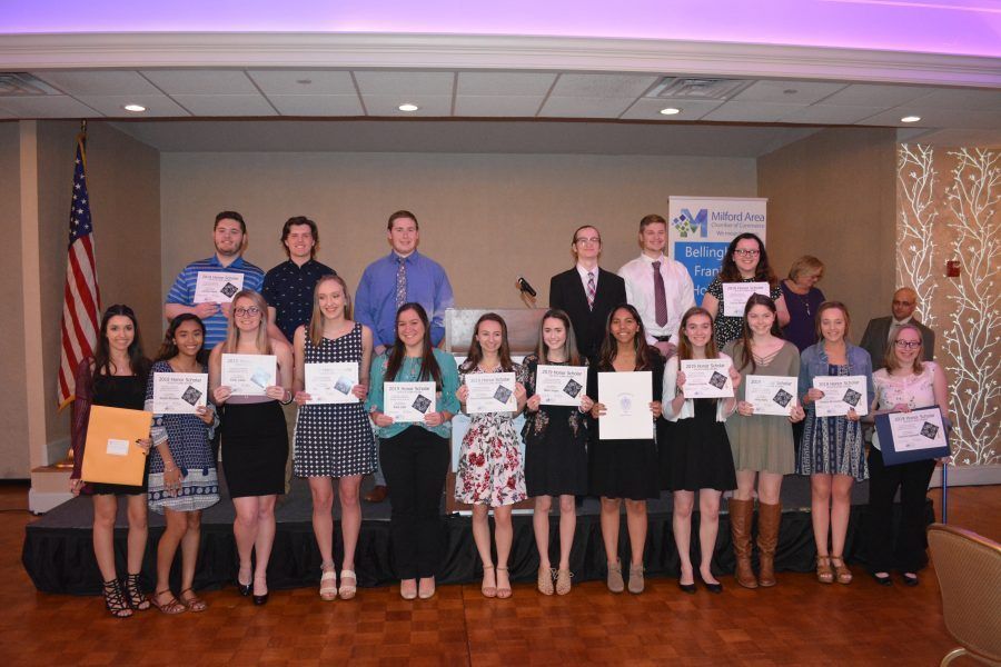 A group of people are standing on a stage holding certificates.