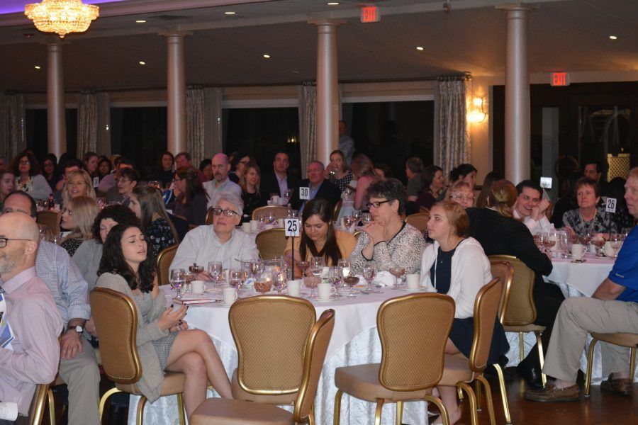 A large group of people are sitting at tables with numbers on them