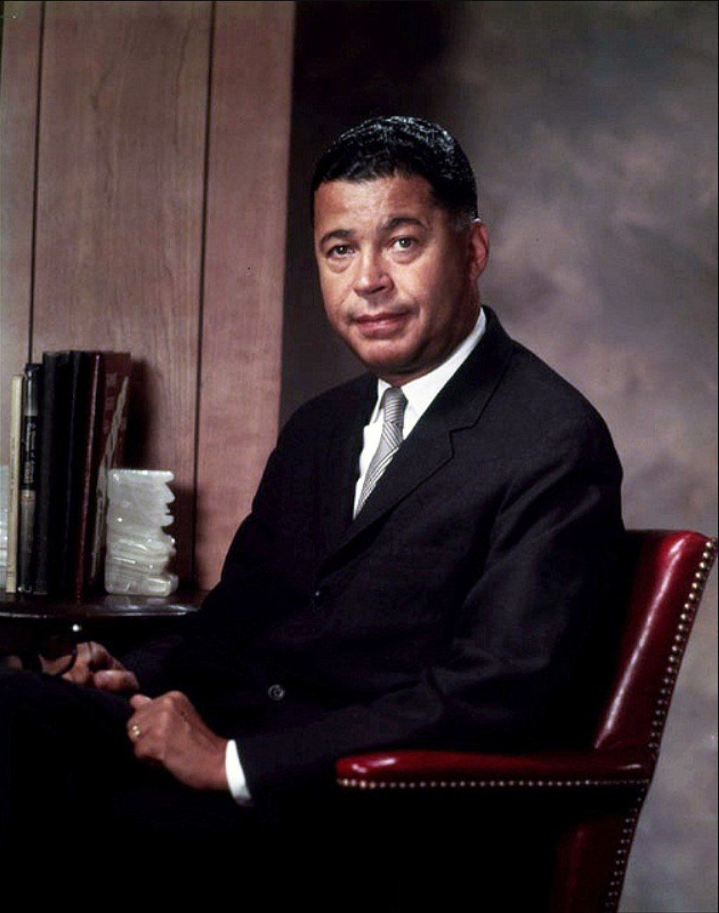 A man in a suit and tie is sitting in a red chair