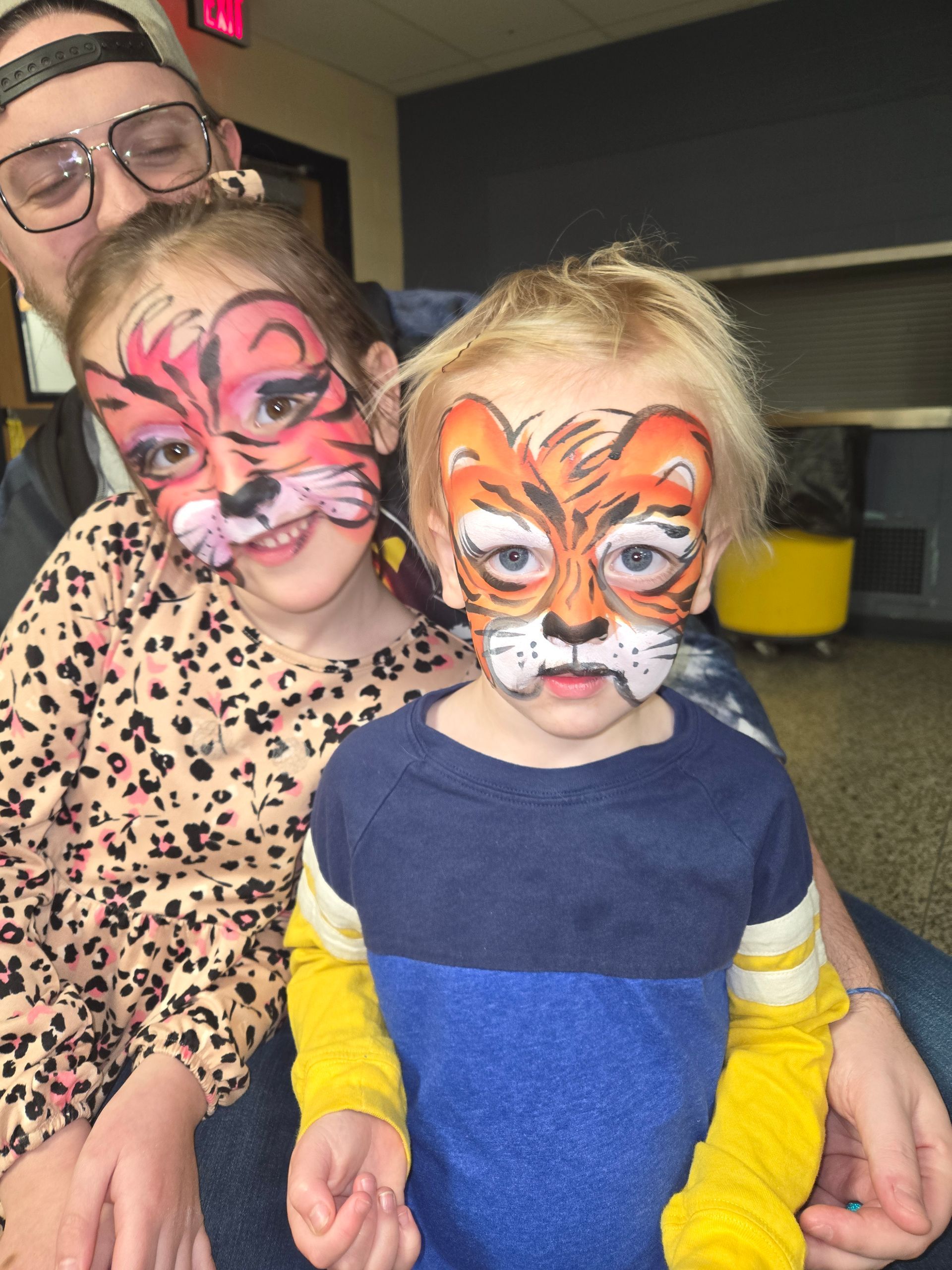 A little girl is getting her face painted by a person.